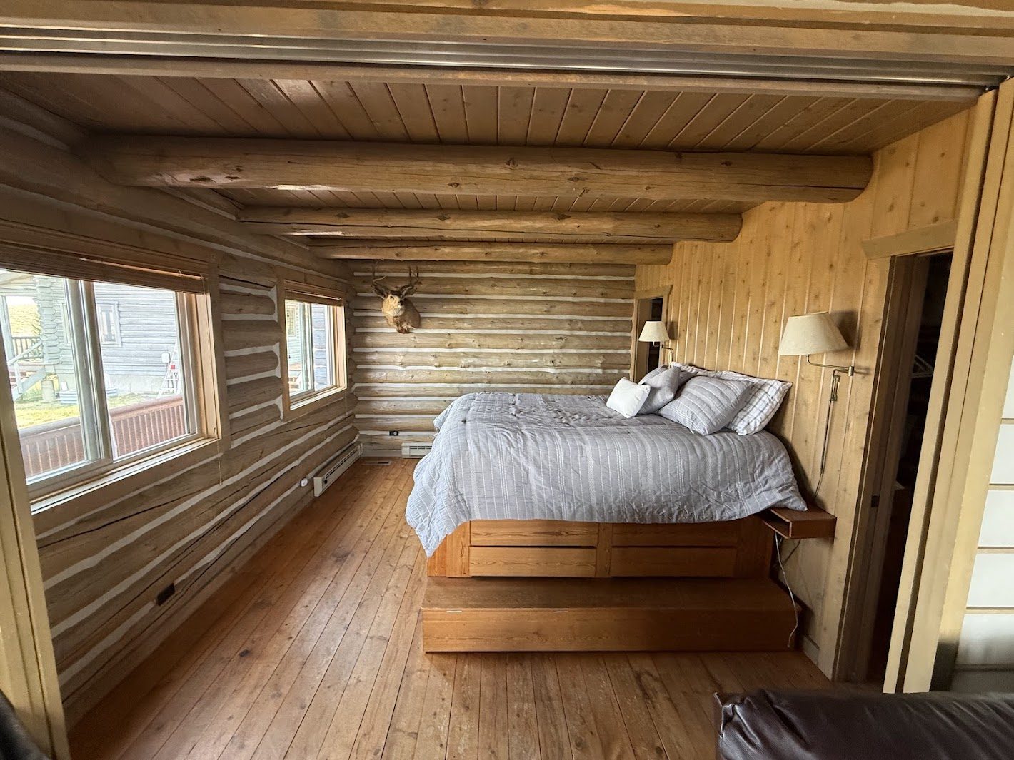Main-floor bedroom — queen platform bed with storage drawers and deer mount