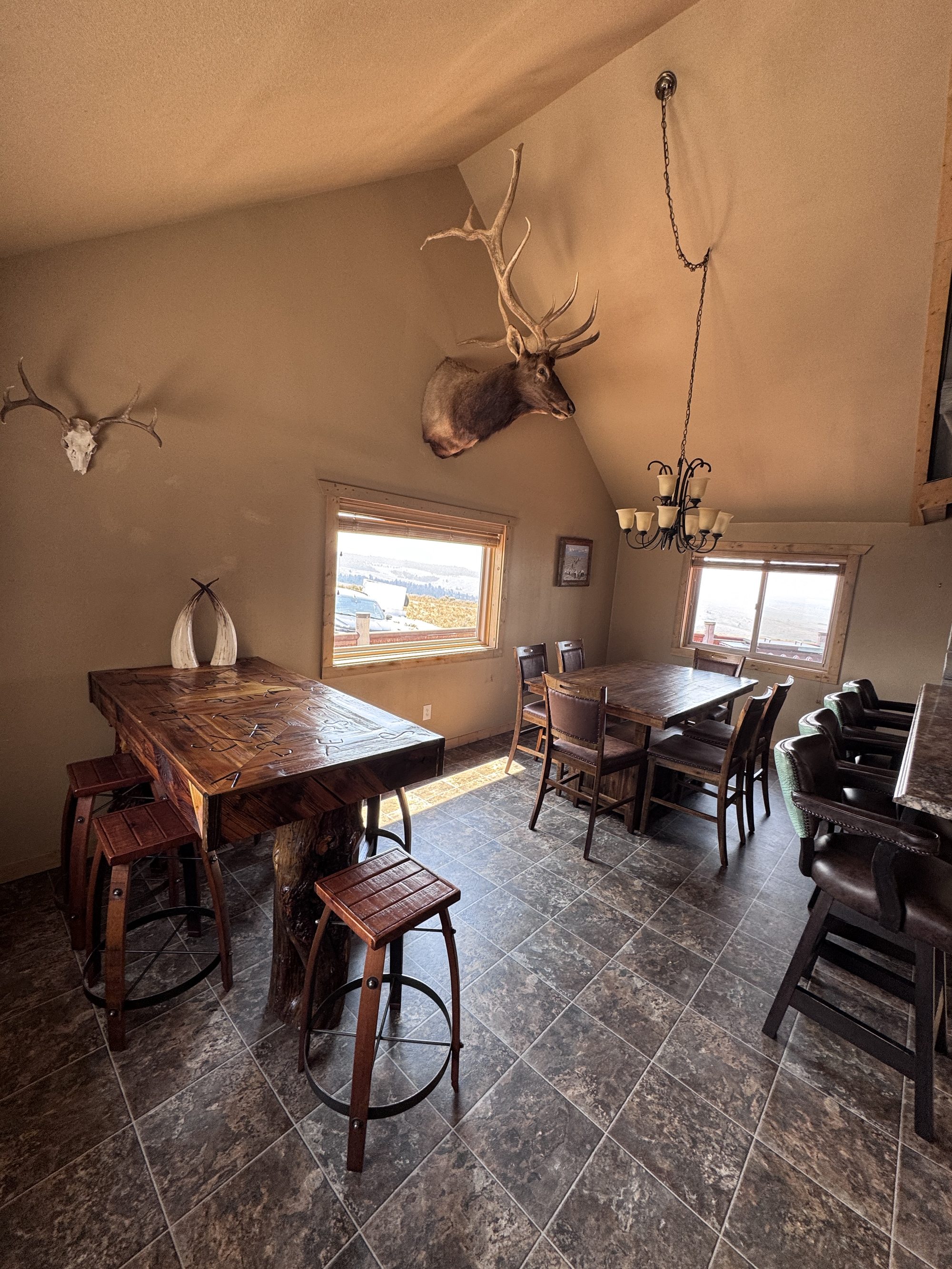 Dining room — two tables, bar seating, and the elk mount overhead