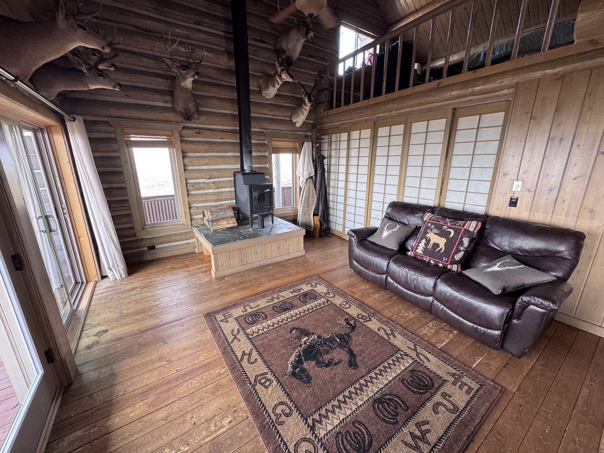 Great room — wood stove on the slate hearth, trophy mounts, and leather seating