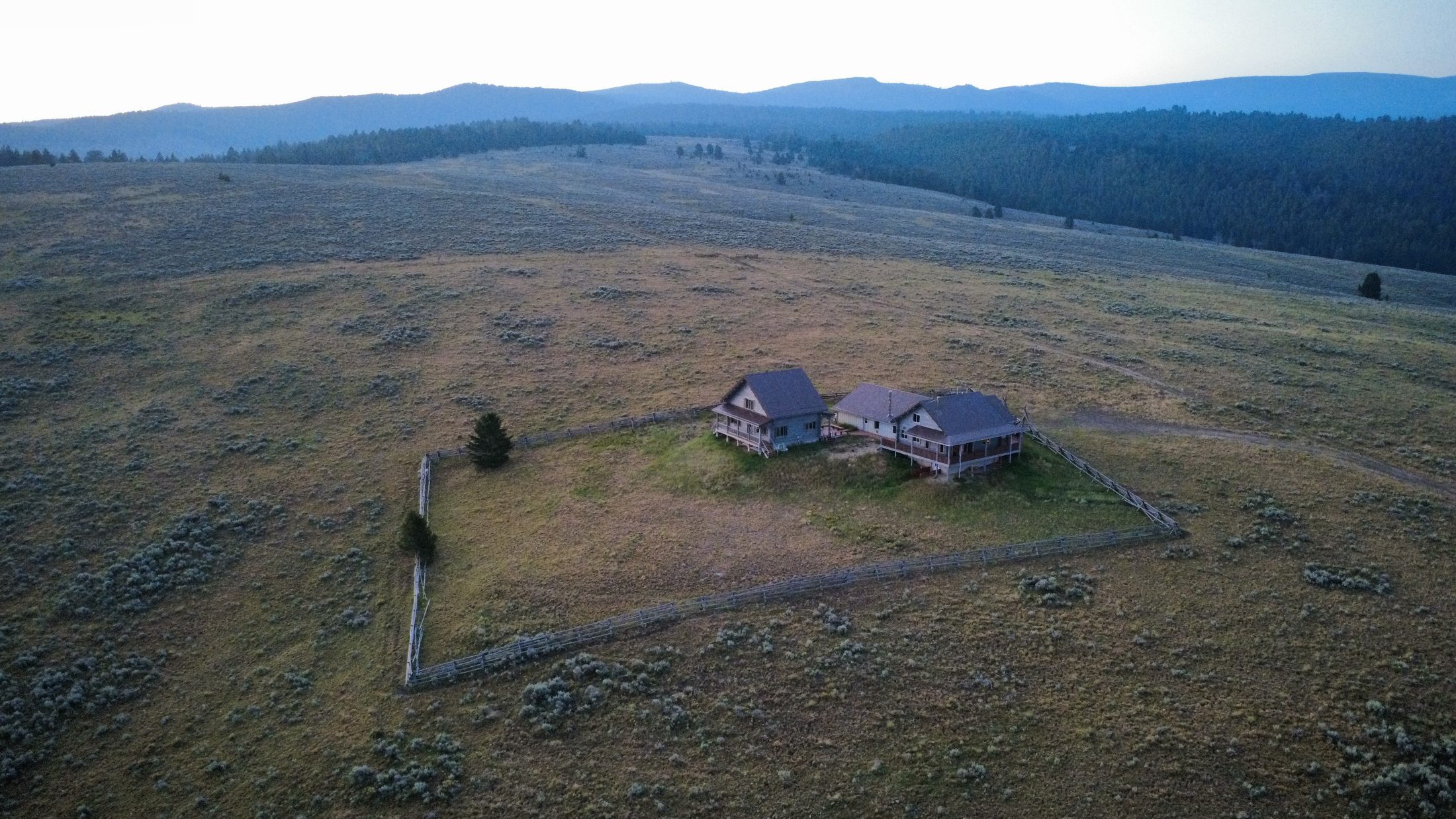 Dawn aerial — the cabins alone on the sage bench