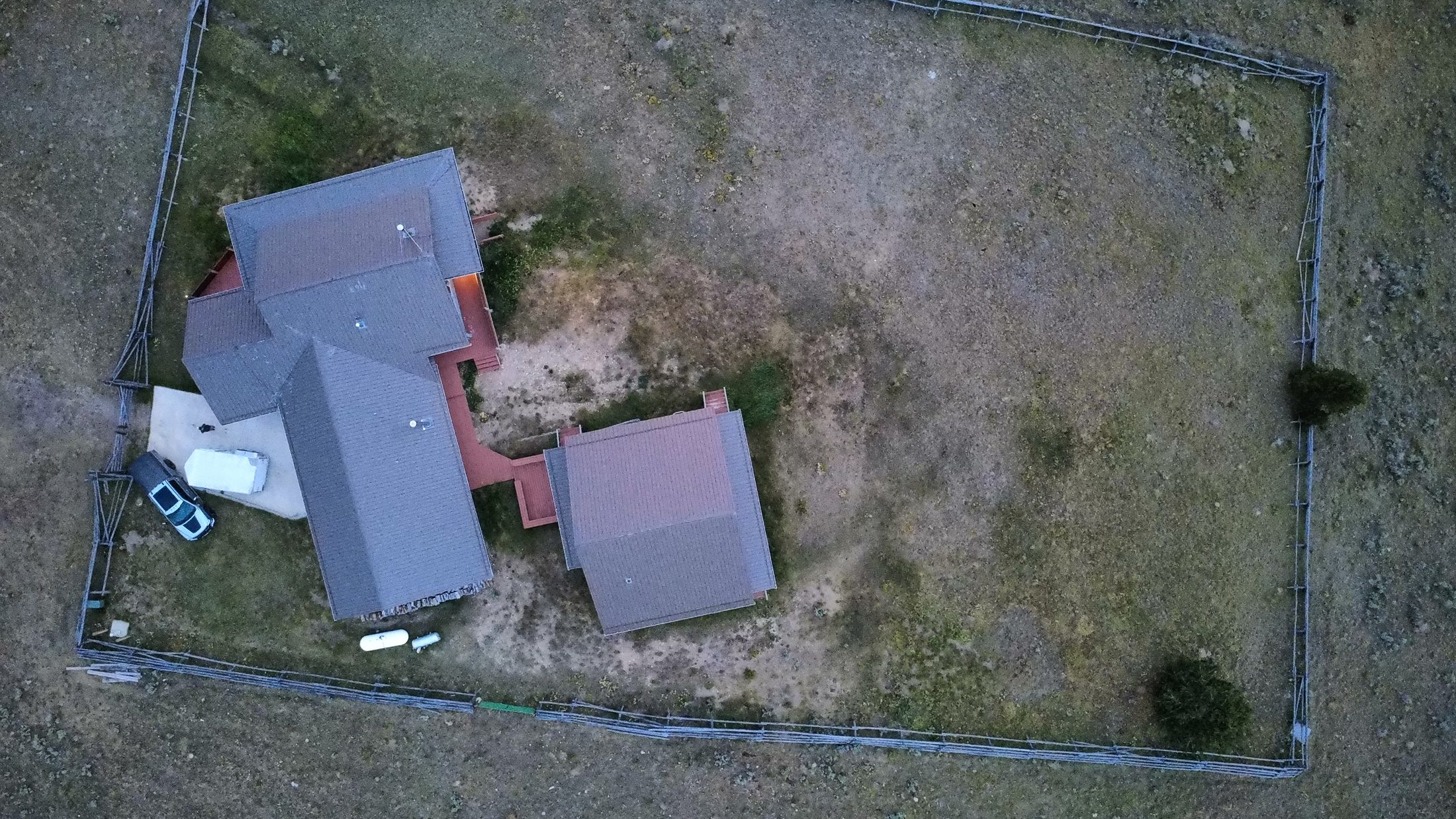 The compound from above — both cabins inside the split-rail fence